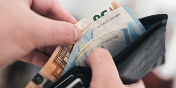 Weiterbildungsgeld Hand greift in Geldbeutel mit einigen Euro-Scheinen