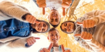 Informationsveranstaltung zum Start Schulversuch 2025 Vier Personen schauen von oben in eine Kamera am Boden und halten die Daumen hoch.
